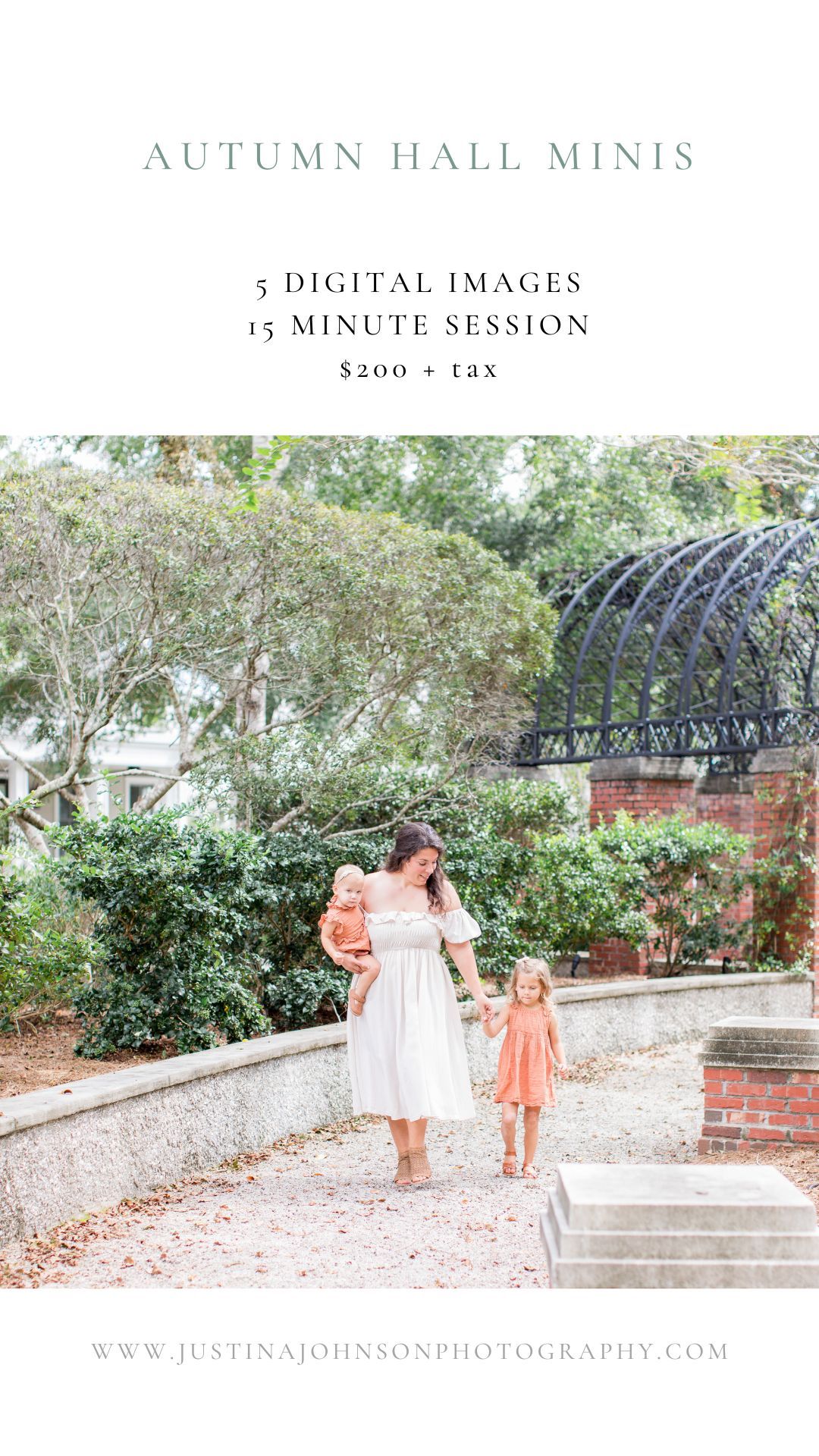 A mother in a white dress holds a baby while walking with a young girl in an outdoor garden setting.