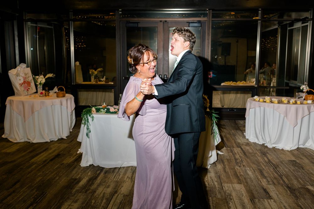 Couple sharing a romantic dance at a wedding reception in an elegant venue with decorated tables in the background.