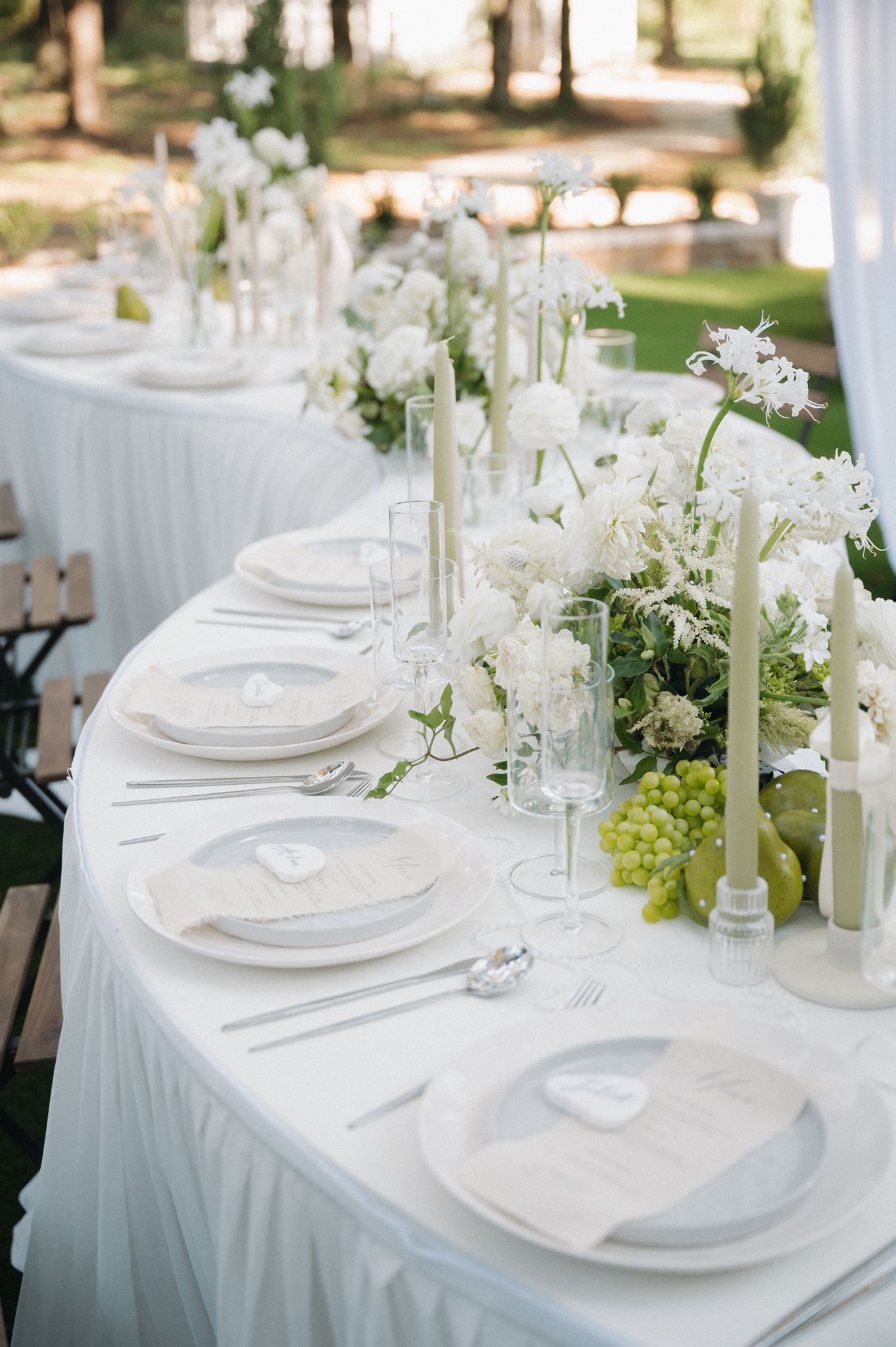 Serpentine wedding reception table with white florals and candles at The Oak Atelier in Conroe, Texas.