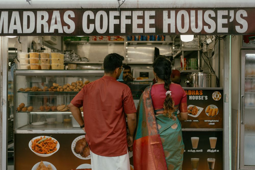 Couple ordering at Madras Coffee House food stall with snacks and beverages on display in Singapore.