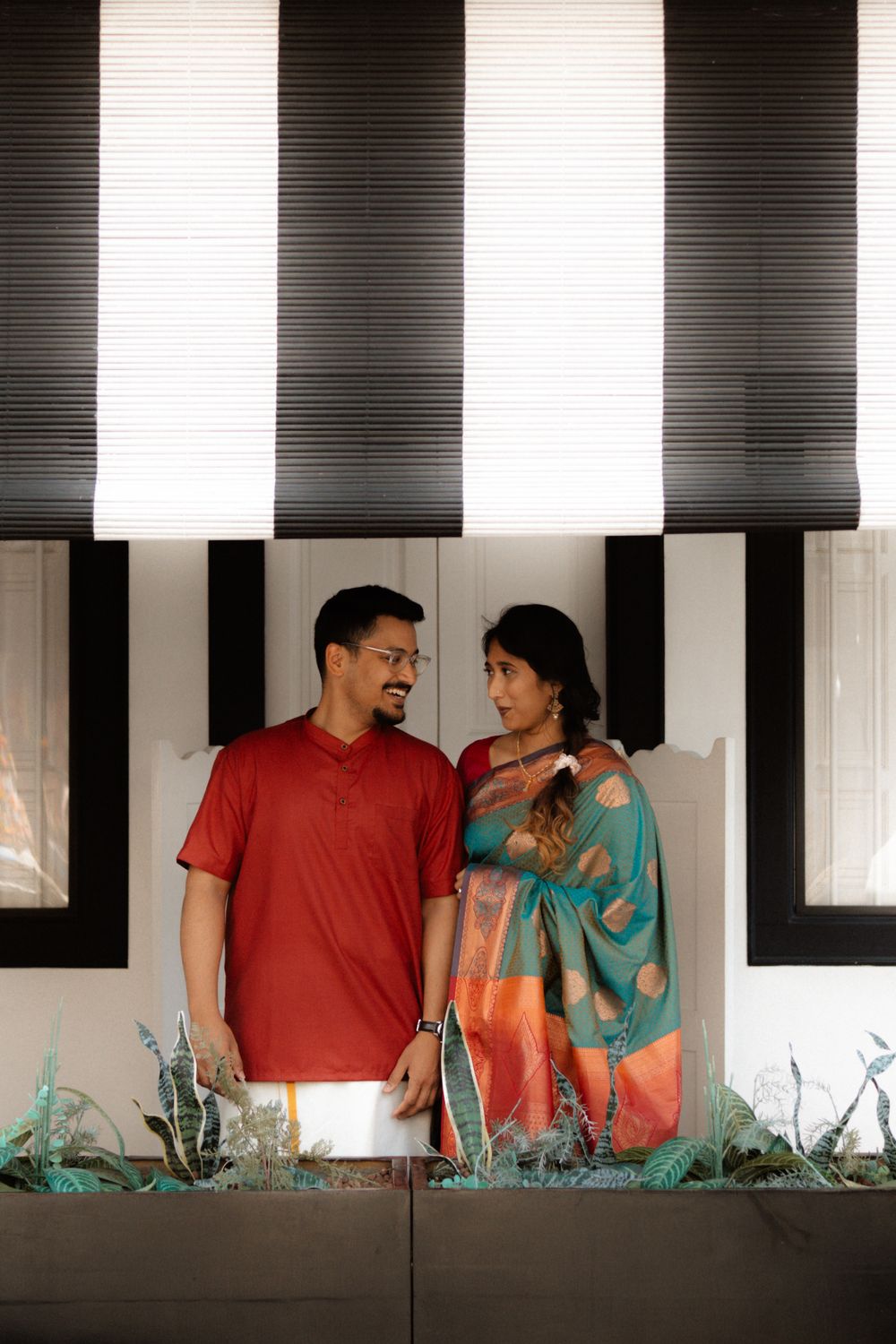 Indian couple in traditional saree and kurta sharing a loving gaze indoors.