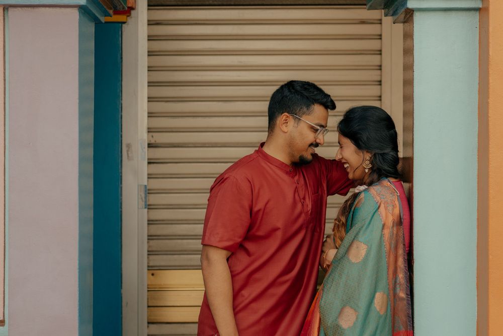 Indian couple in traditional attire sharing a romantic moment outdoors near a shutter door.