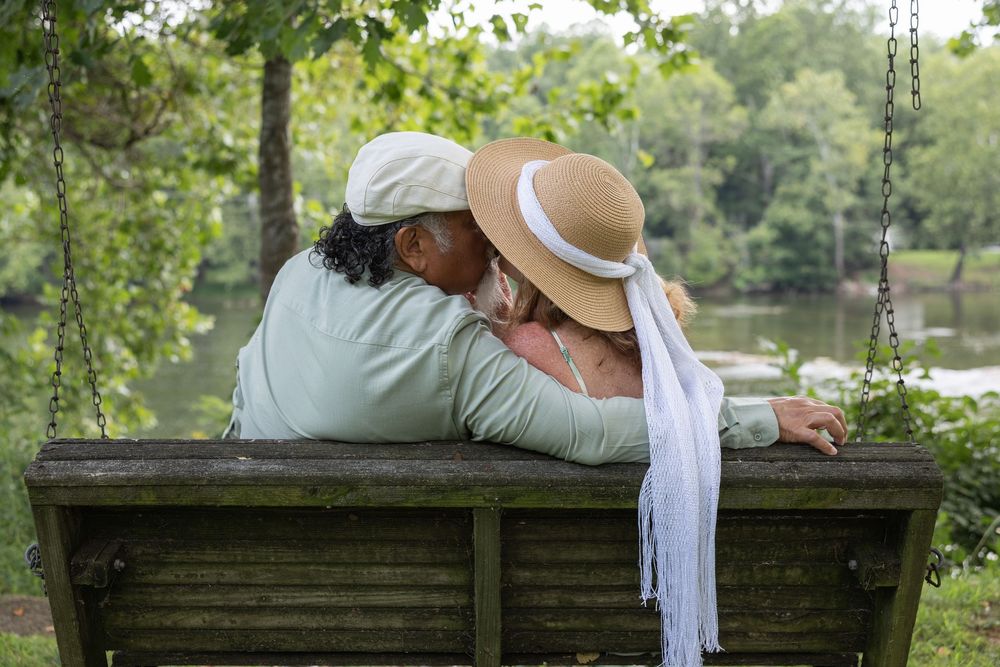Karen and George kissing on a swing by the river after their microwedding in Luray