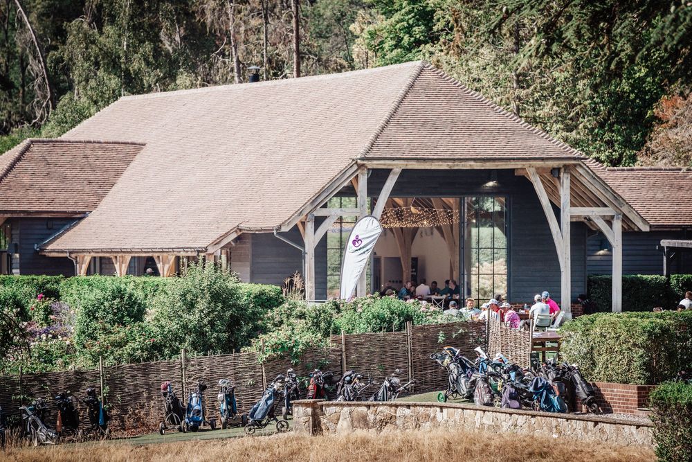 Golf club exterior with rows of golf bags and equipment outside a rustic wooden clubhouse.