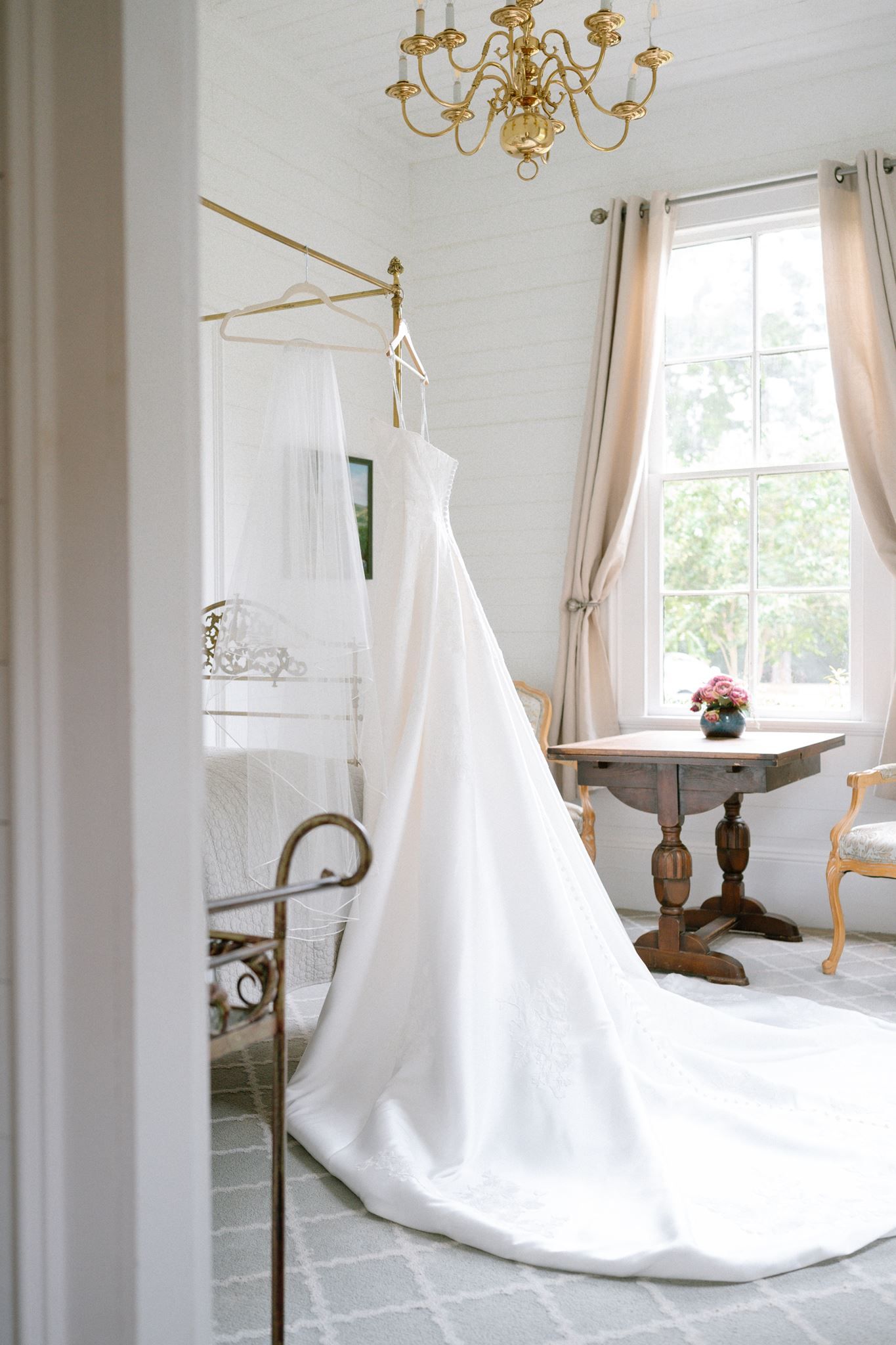 Bridal gown hanging in a white room at Historic Hill House in Willis Texas.