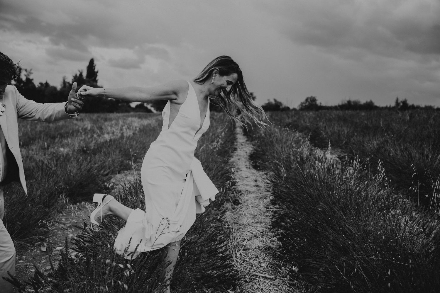 A romantic black and white wedding photograph showing a tender embrace in a natural outdoor setting.