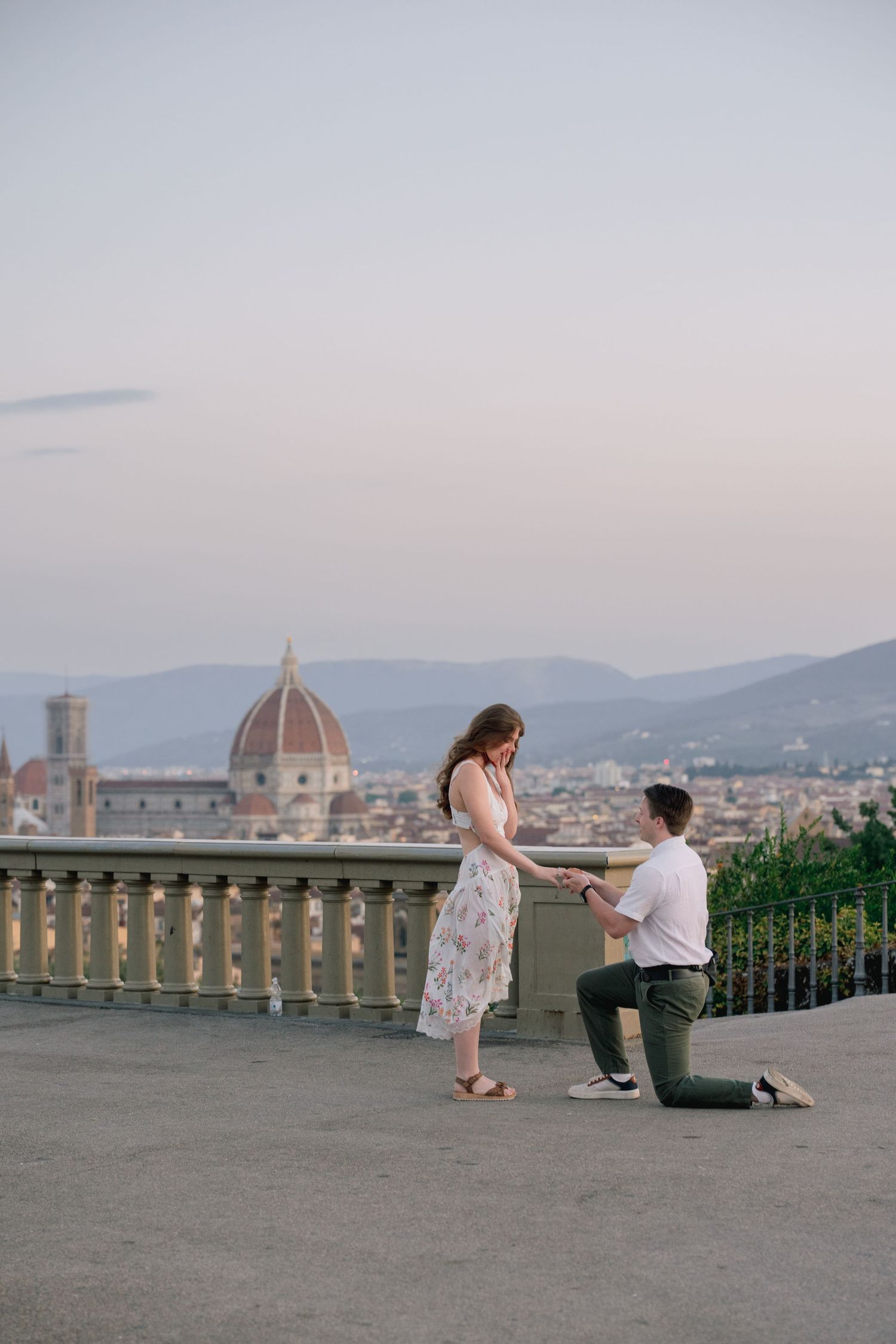 Romantic marriage proposal on knee in Florence Italy with stunning Duomo cathedral skyline at sunset.