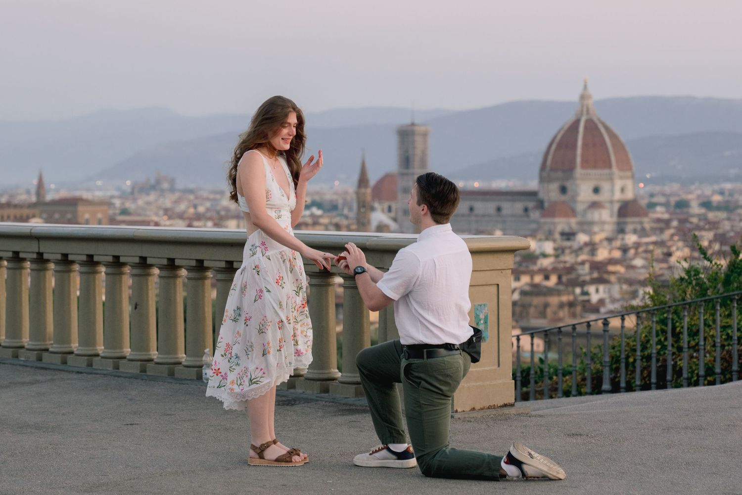 Man proposes to woman on one knee at Piazzale Michelangelo with Florence skyline and Duomo at sunset.