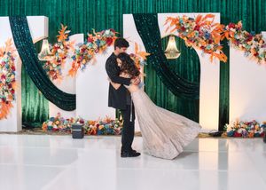 Bride and groom sharing a kiss at a vibrant wedding altar adorned with colorful floral arrangements.
