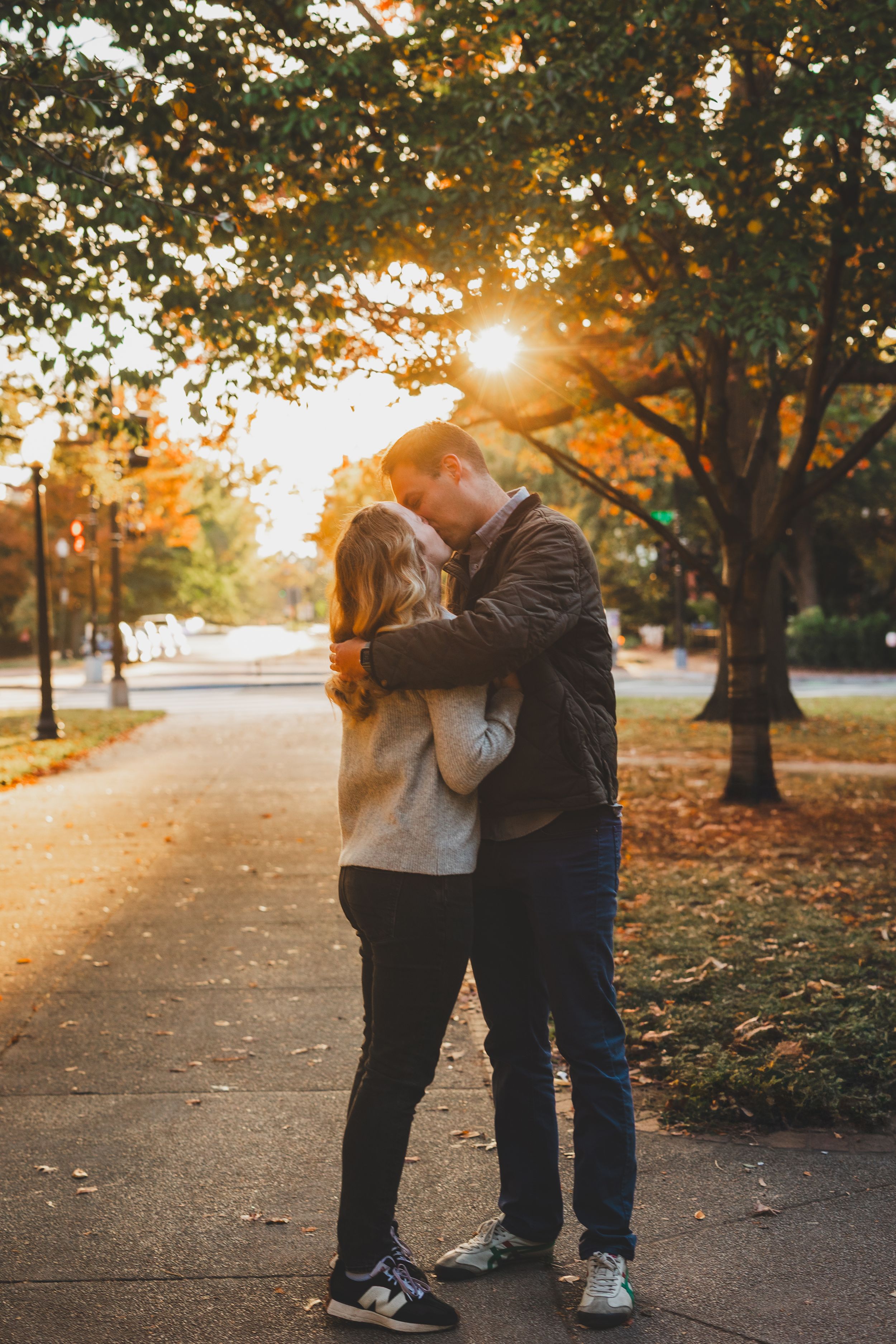 Couple sharing a romantic kiss on a tree-lined path during golden hour in autumn at the Stanton Park In Washington DC