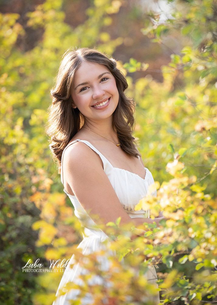 Fall portrait of a senior girl in white dress by photographer Luba Wold in Post Falls