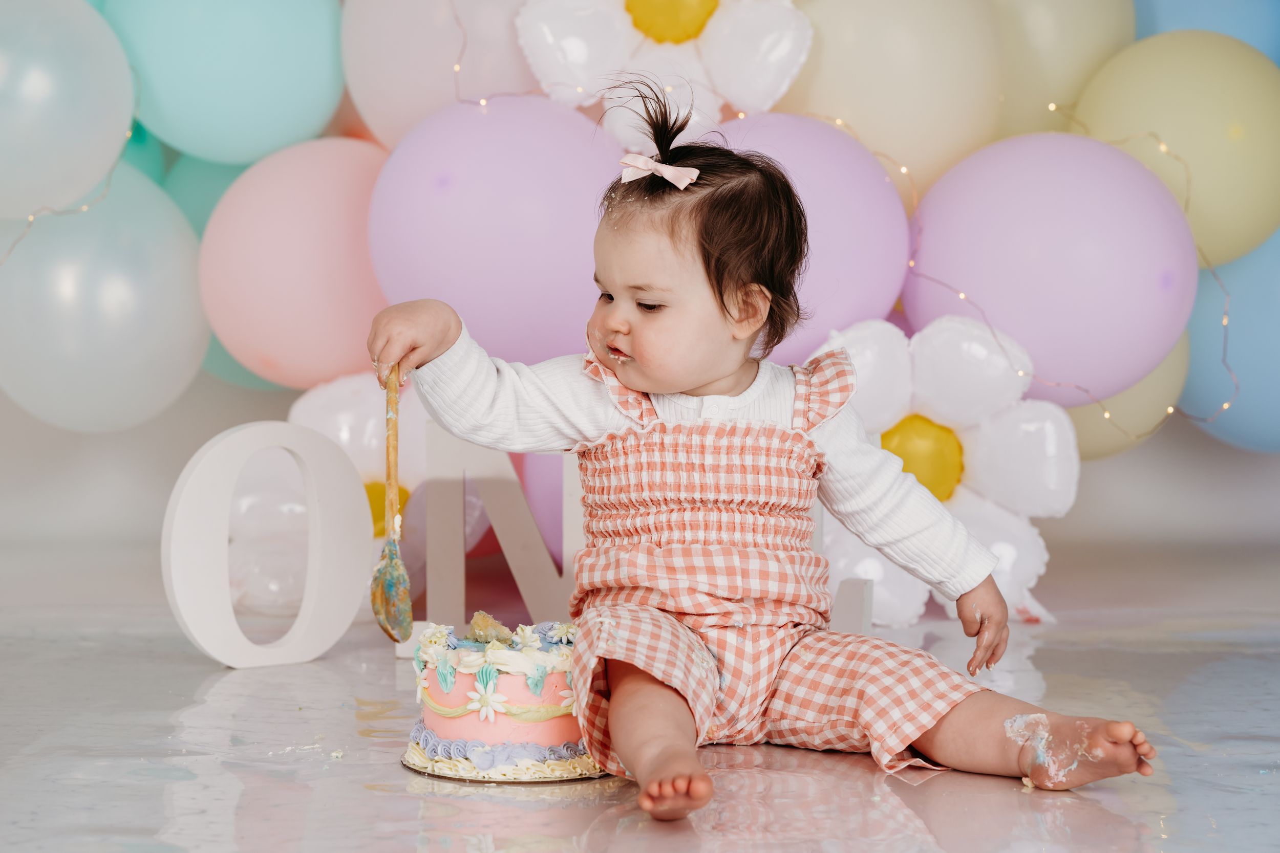 Colorful balloon installation with pastel shades set up for first birthday cake smash photos.