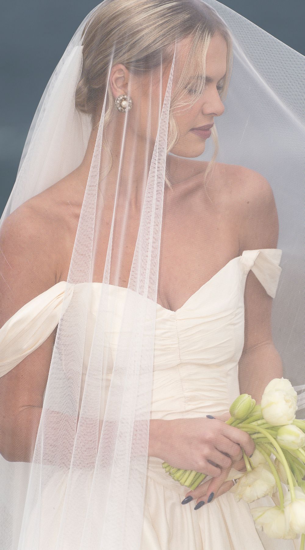 A bride in a classic white wedding gown poses with a delicate veil and white bouquet in a series of elegant portraits.
