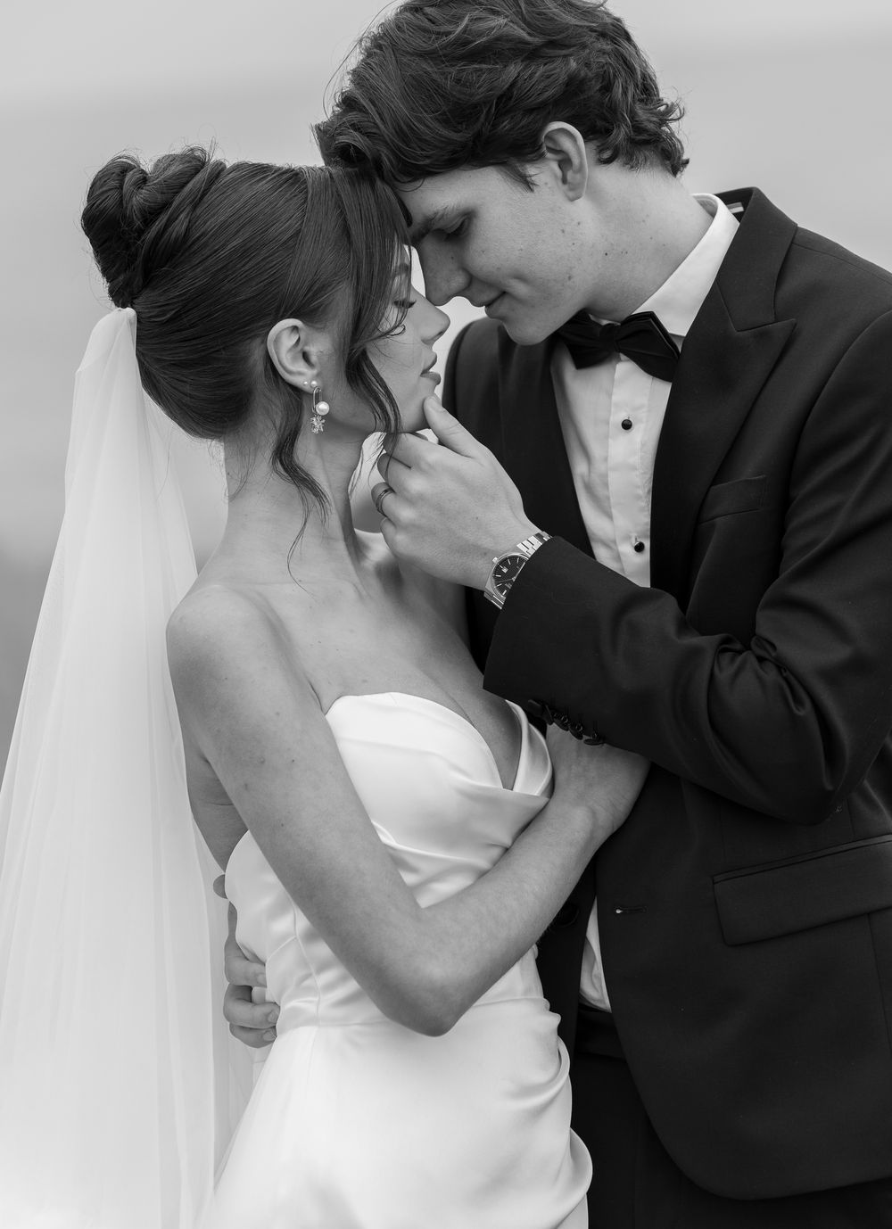 Black and white wedding photos capture tender moments between newlyweds in classic formal wear.
