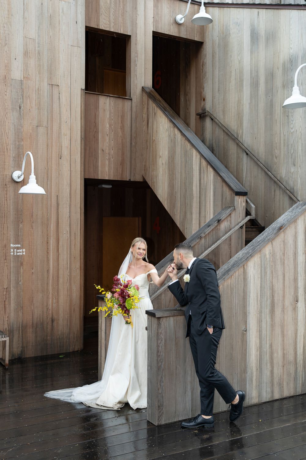 Wedding couple poses playfully in sequence against wooden wall with industrial lighting.