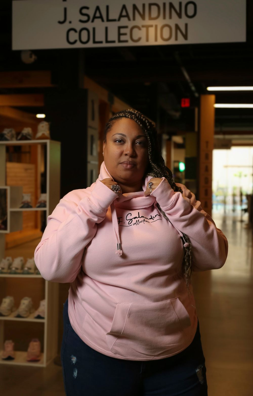 Someone poses in a pink sweatshirt in front of the J. Salandino Collection display at a retail store.