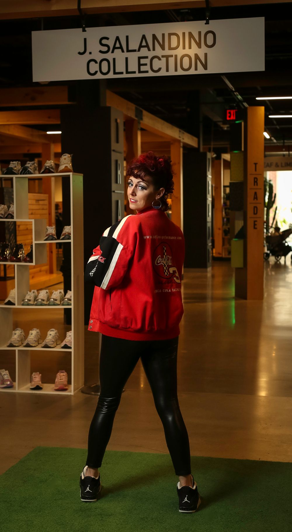 A person in a red varsity jacket and black pants poses in front of a J. Salandino Collection store display.