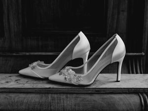 Elegant white bridal shoes arranged in artistic black and white composition.
