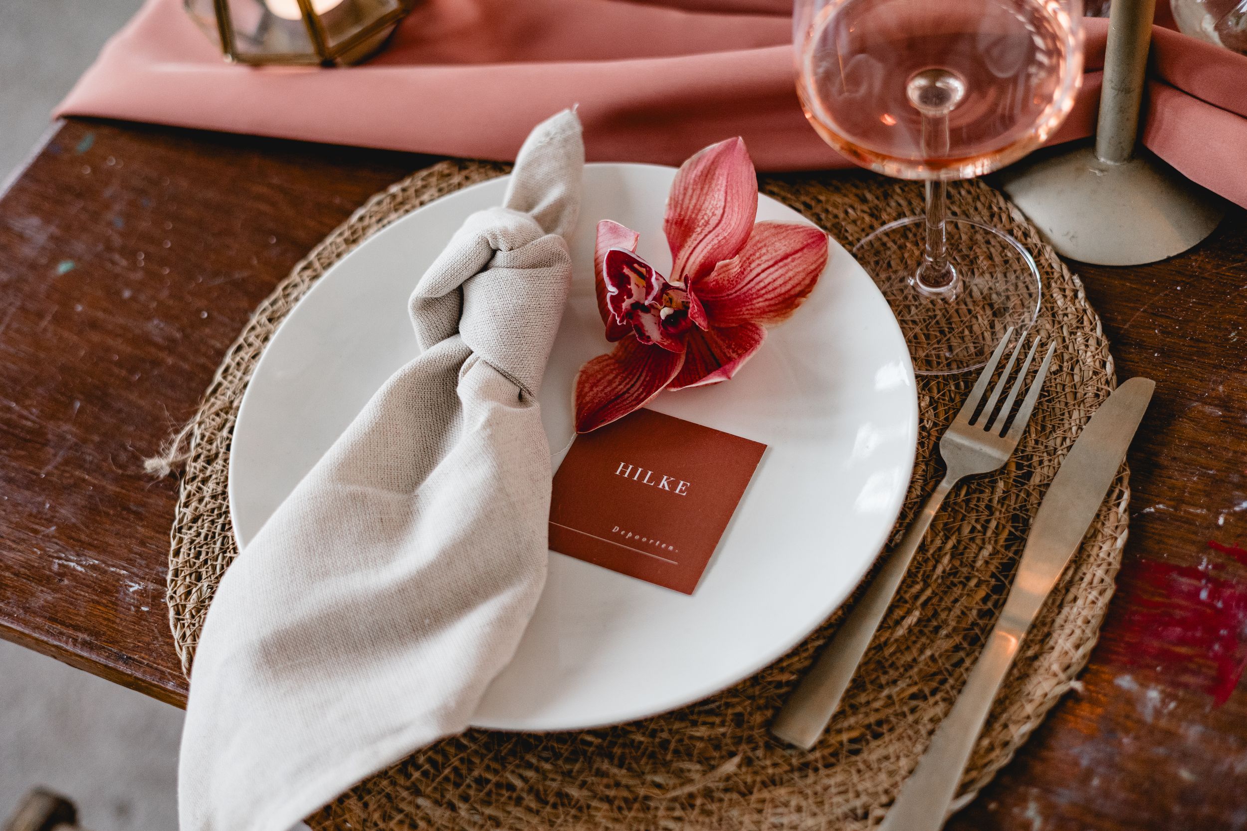 Rustic wedding table details featuring pink napkins and delicate place settings.