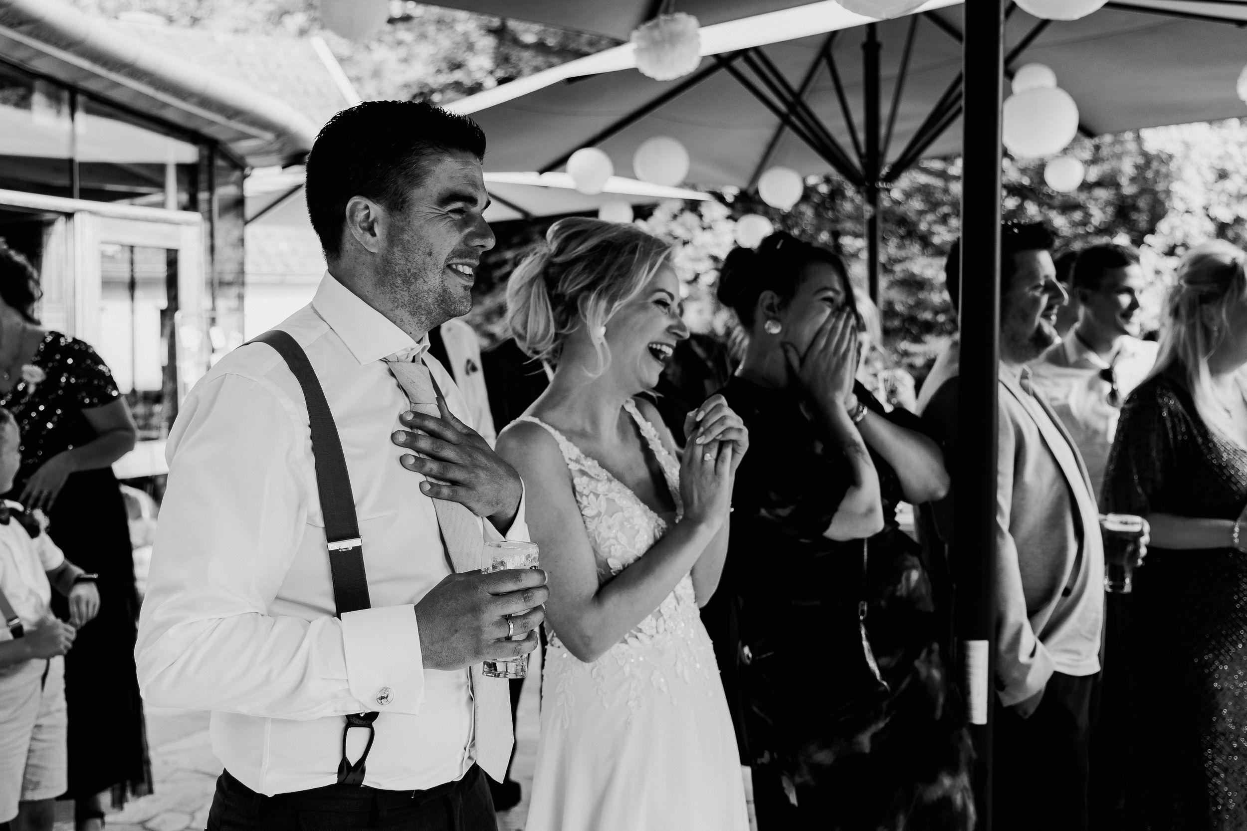 Wedding celebration with guests holding white parasols outdoors.