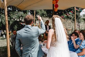 Wedding reception celebration under a tent with hanging lanterns and decorations.