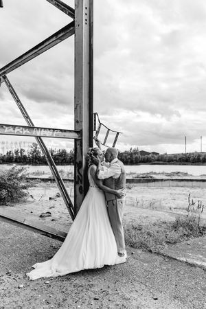 Wedding couple posing against industrial metal beams in an urban setting.