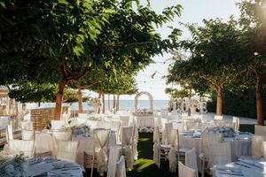 Elegant outdoor wedding reception setup with white-draped tables and chairs overlooking a scenic ocean view.
