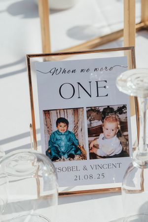 A series of wedding table place cards with vintage photographs and text displayed in a white elegant setting.