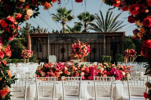 White chairs arranged for an outdoor wedding ceremony with vibrant red bougainvillea flowers framing the scene.