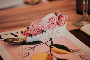Pink floral wedding table decorations with place cards and rose petals create an elegant romantic setting.