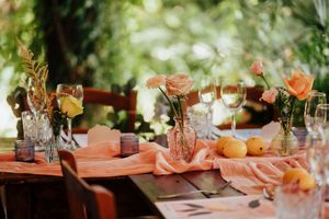 Outdoor wedding reception tables decorated with pink linens and floral arrangements in a garden setting.