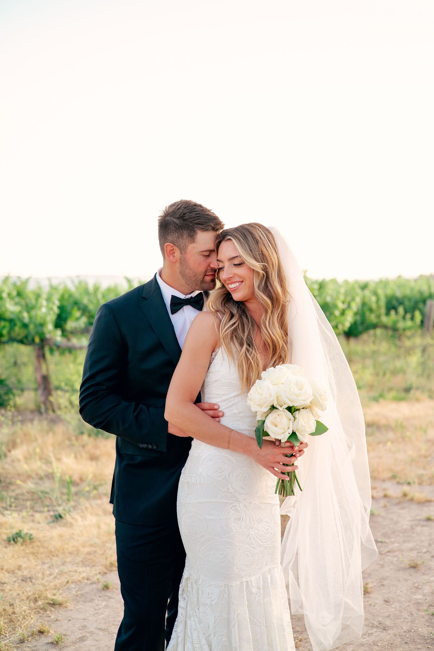 Romantic wedding portraits taken in a sunny vineyard setting.