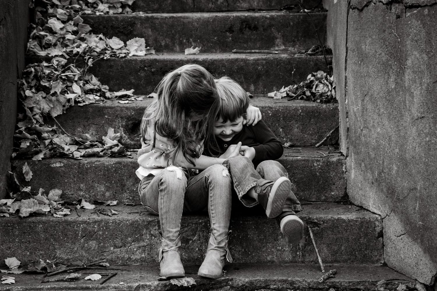 black-and-white photo of two children sitting on outdoor steps in the fall.