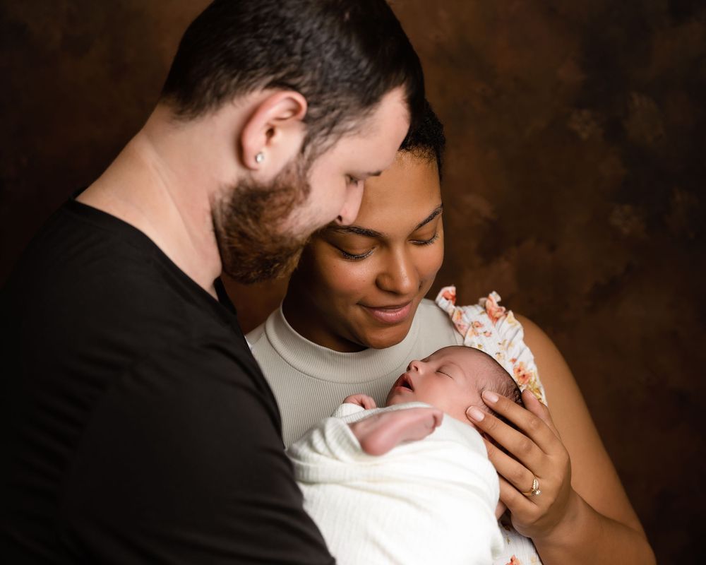 A tender family moment captured in a dark and intimate setting with a newborn baby.