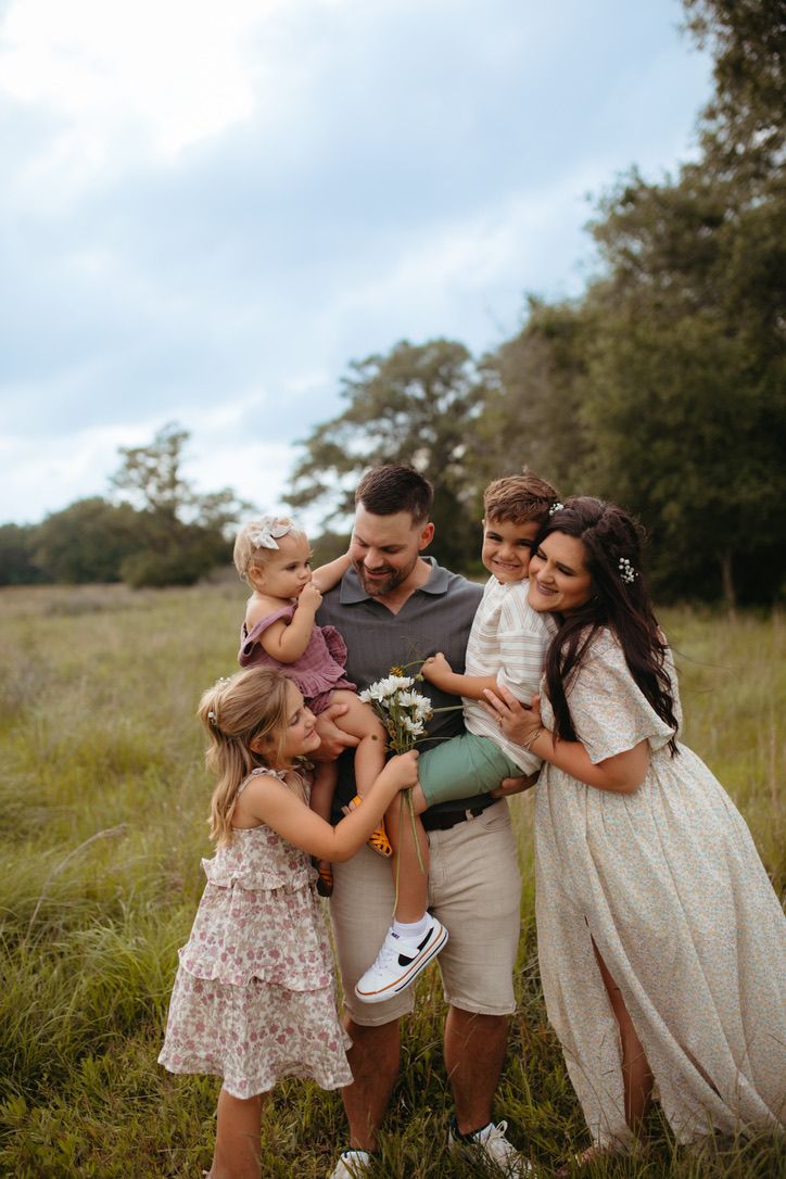 A joyful family sharing a candid moment together in an open field at sunset.
