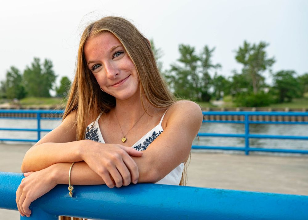 Summer portrait session by a blue railing near the water.