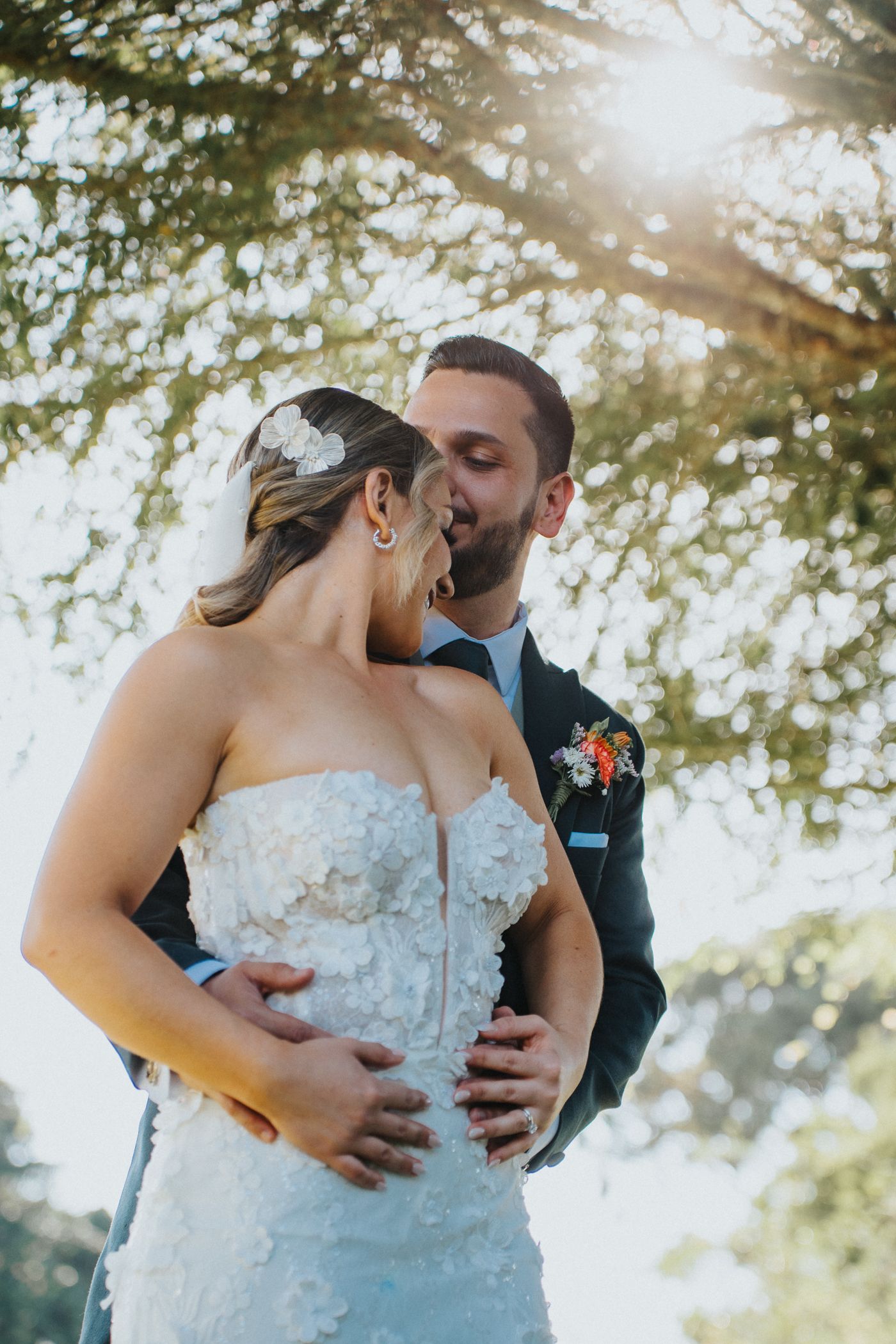 Novios abrazados al aire libre con luz natural en boda / Bride and groom embracing outdoors in natural wedding light.