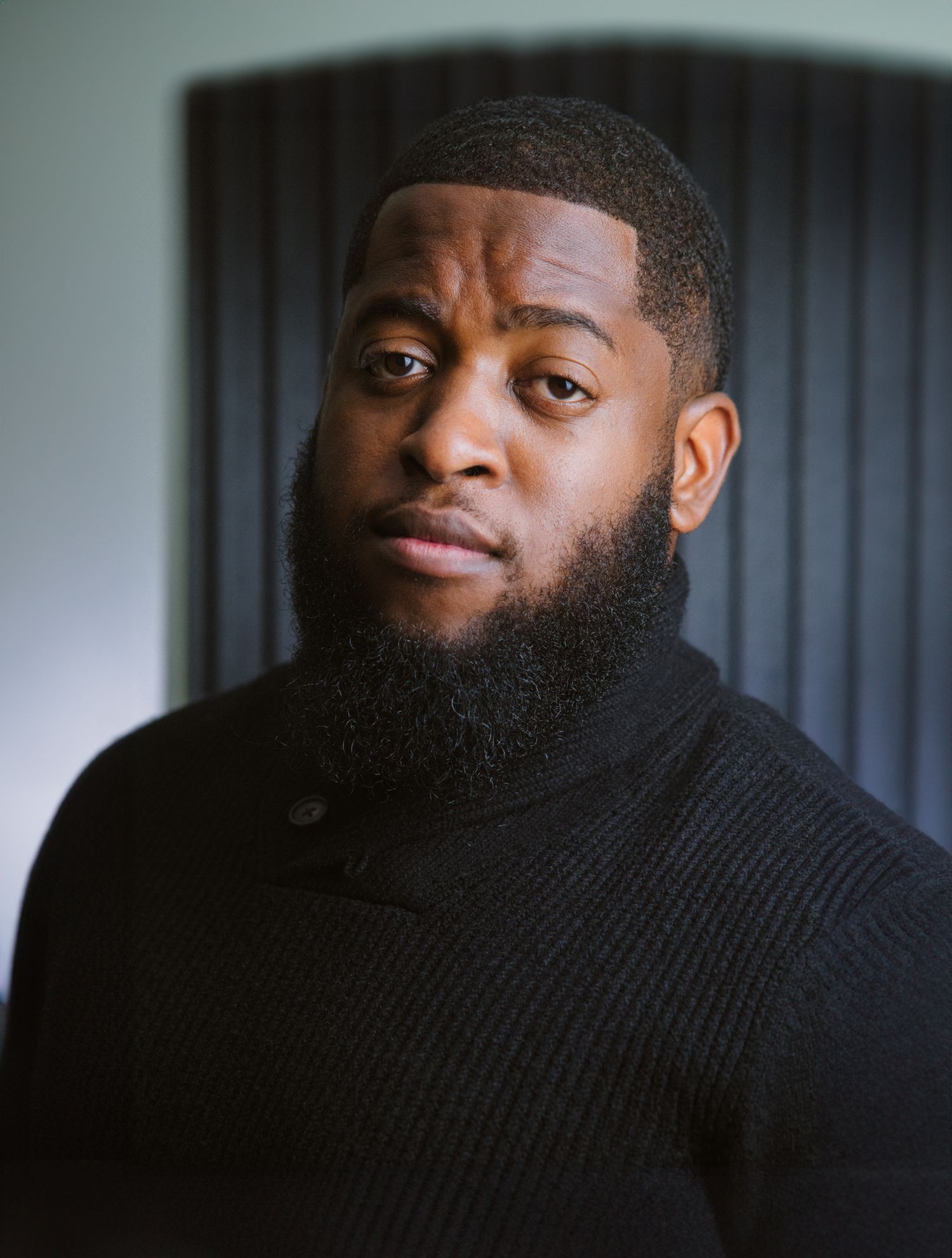 Portrait of person in black sweater against gray background.