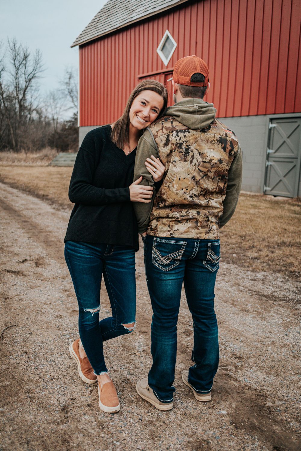 Casual couple photos by red barn in matching denim and casual wear.