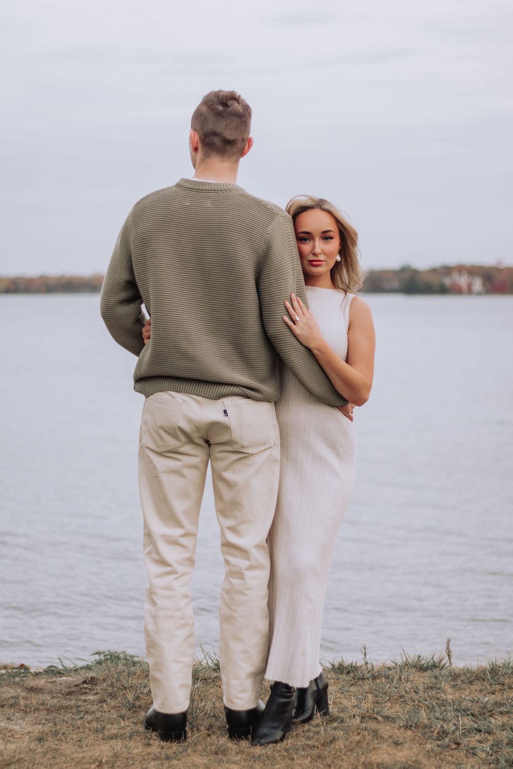 Couple in casual attire sharing an intimate moment by the waterfront at sunset.