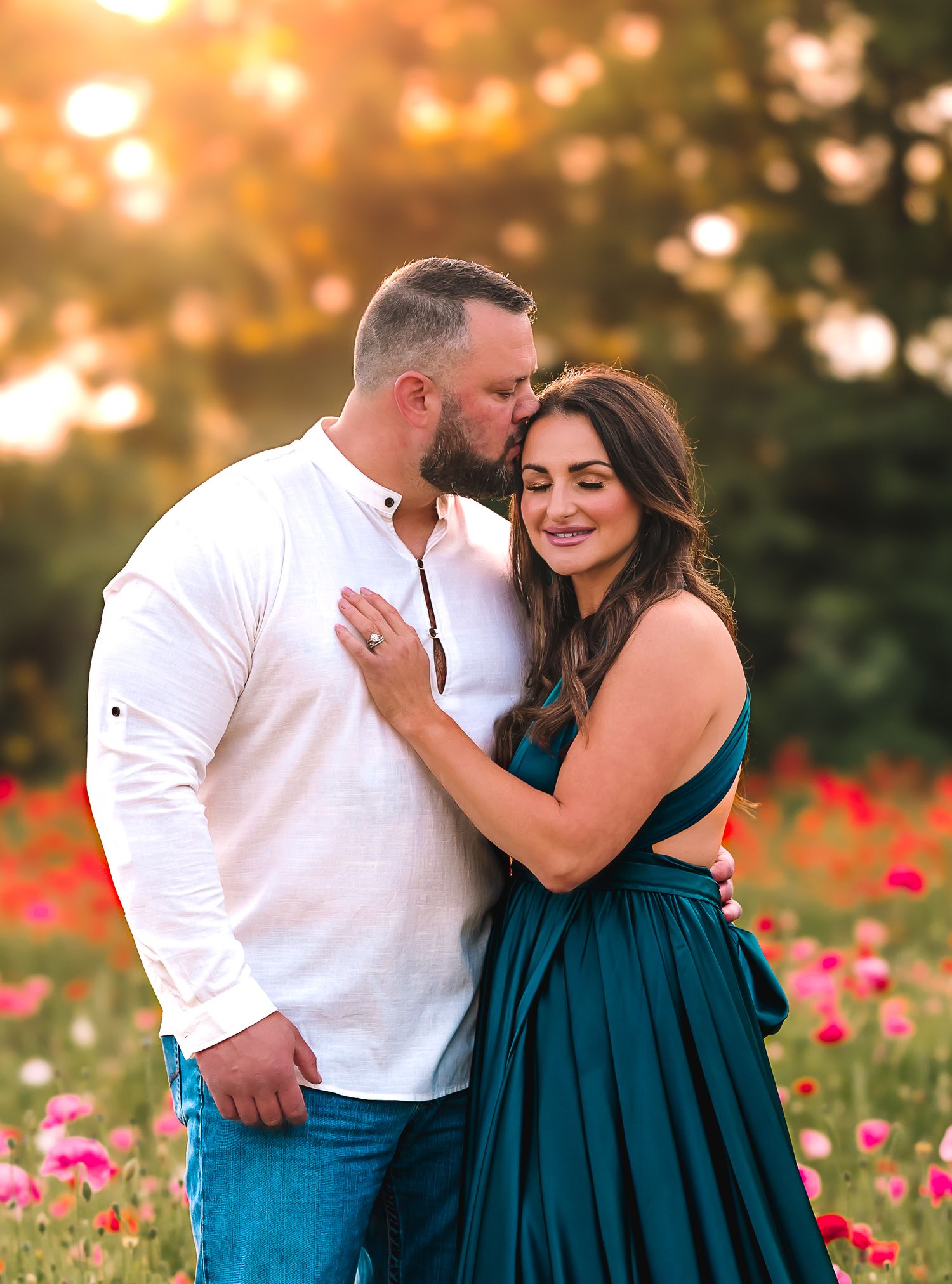 Romantic couple portraits in a field of red poppies at sunset wearing white and teal outfits.