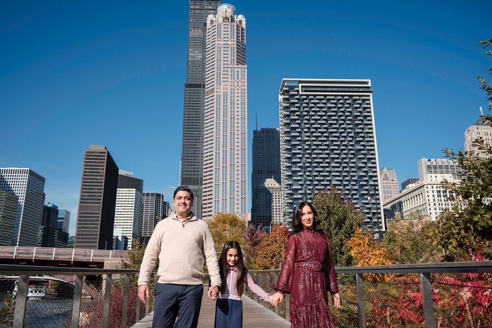 Group of people enjoy autumn foliage with Chicago skyline and skyscrapers in background on sunny day.