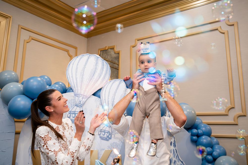 Wedding celebration with blue balloons and sparkling lights in an ornate room with gold-trimmed walls.
