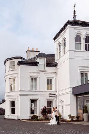 Beautiful white Victorian-style mansion with curved facade and tower serves as an elegant wedding venue in the British countryside.