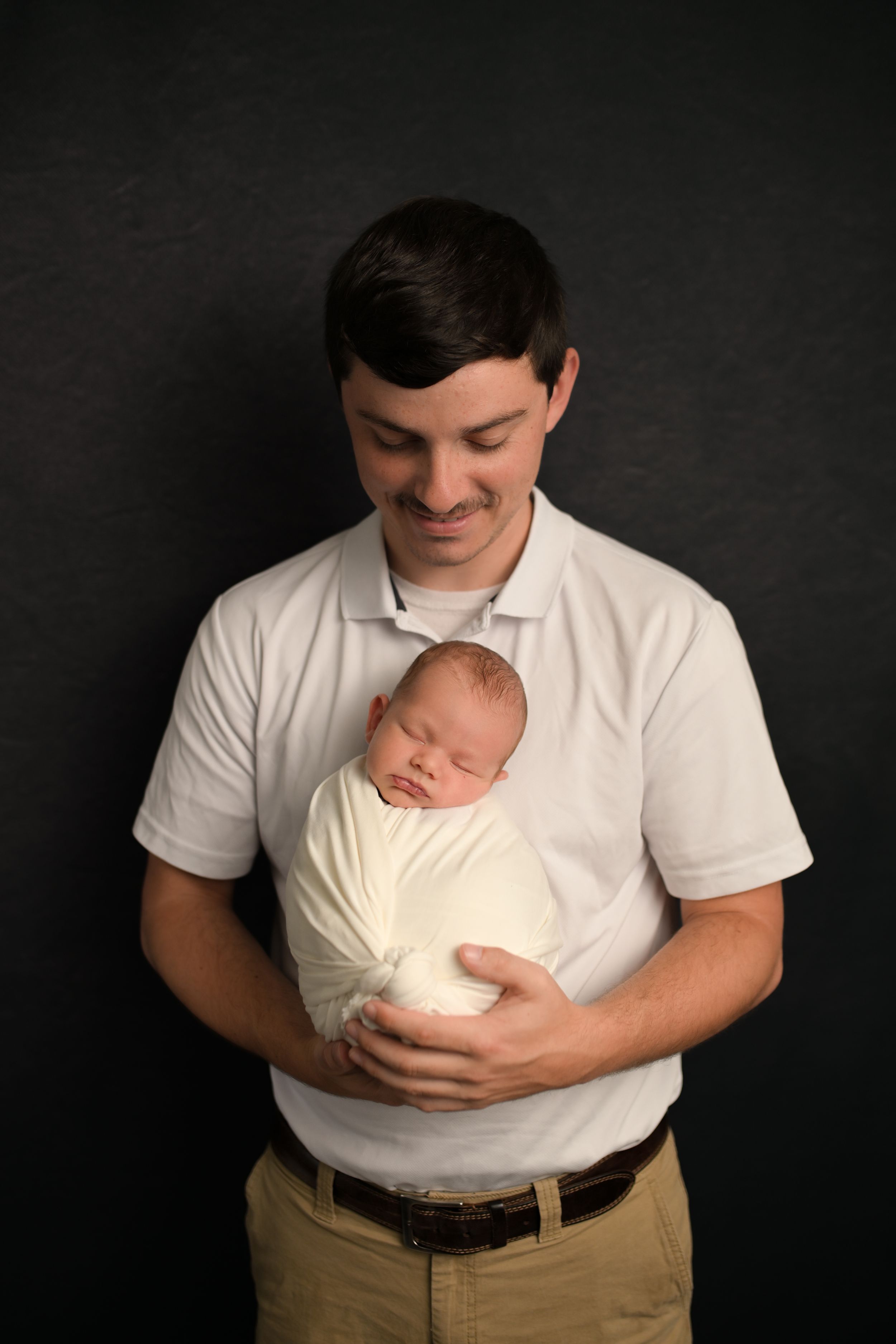 Professional newborn photography session against dark background.