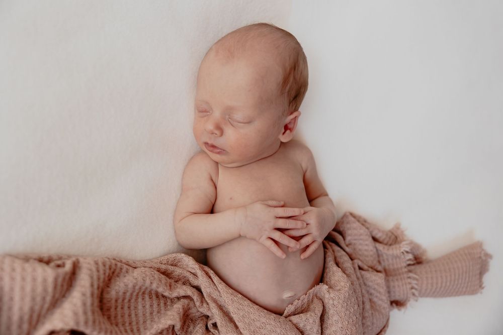 Newborn baby sleeping peacefully on soft beige blanket in natural light. In studio in Oostburg, WI  with Essence Rose Photography.