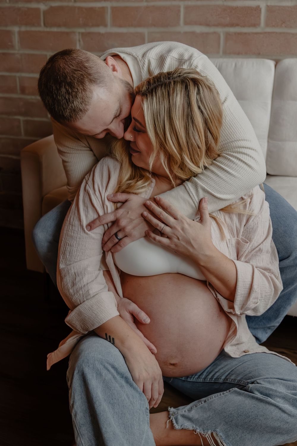 Intimate in studio maternity photo session showing a couple embracing on a couch. in Oostburg, WI  with Essence Rose Photography.
