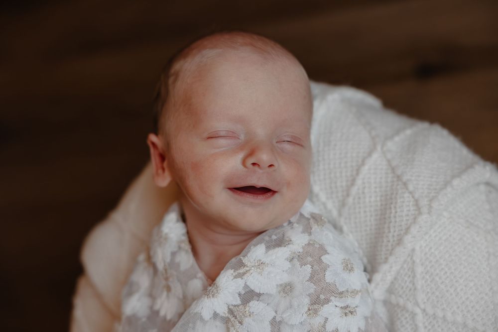 Smiling newborn portraits in studio showing baby wrapped in delicate white lace. in Oostburg, WI  with Essence Rose Photography.
