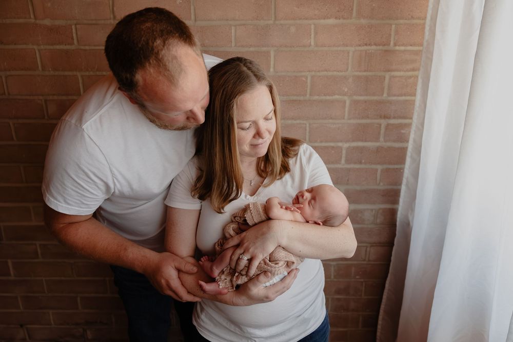 Family newborn portrait session with baby against brick wall background in Oostburg, WI  with Essence Rose Photography.