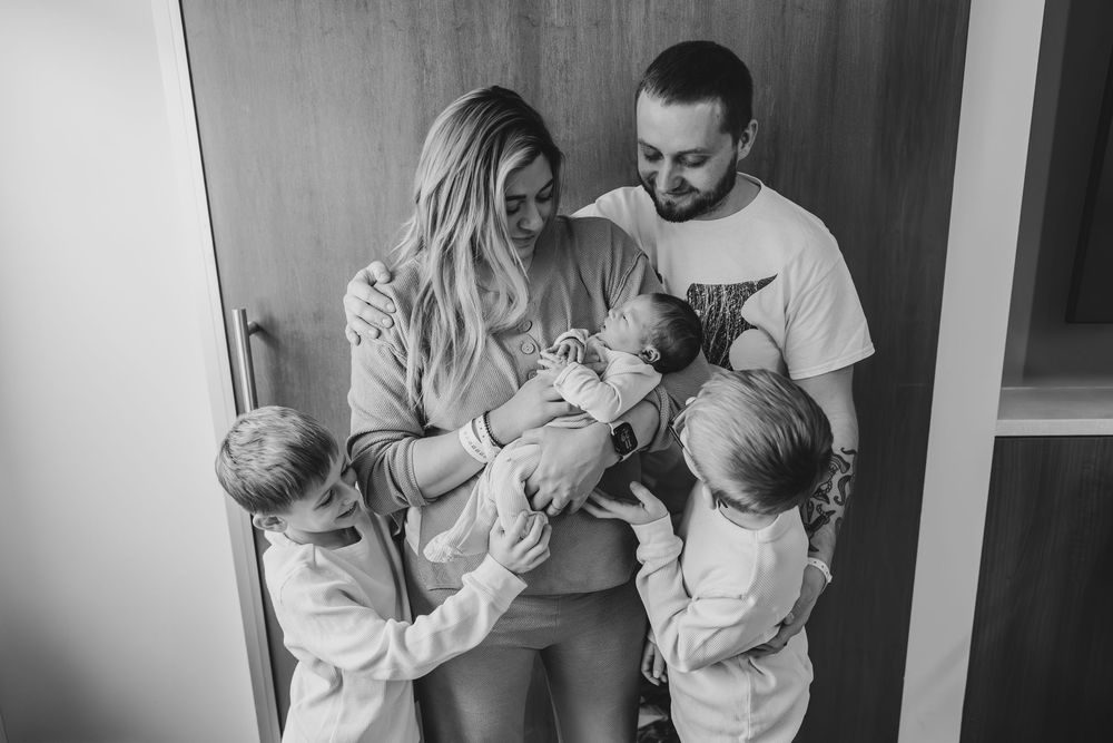 Black and white photo of a family bonding with their newborn at home. Fresh48 in hospital session in Sheboyga, WI  with Essence Rose Photo.